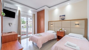 A hotel room with two beds, a desk, a TV, and a sliding glass door to the outside.
