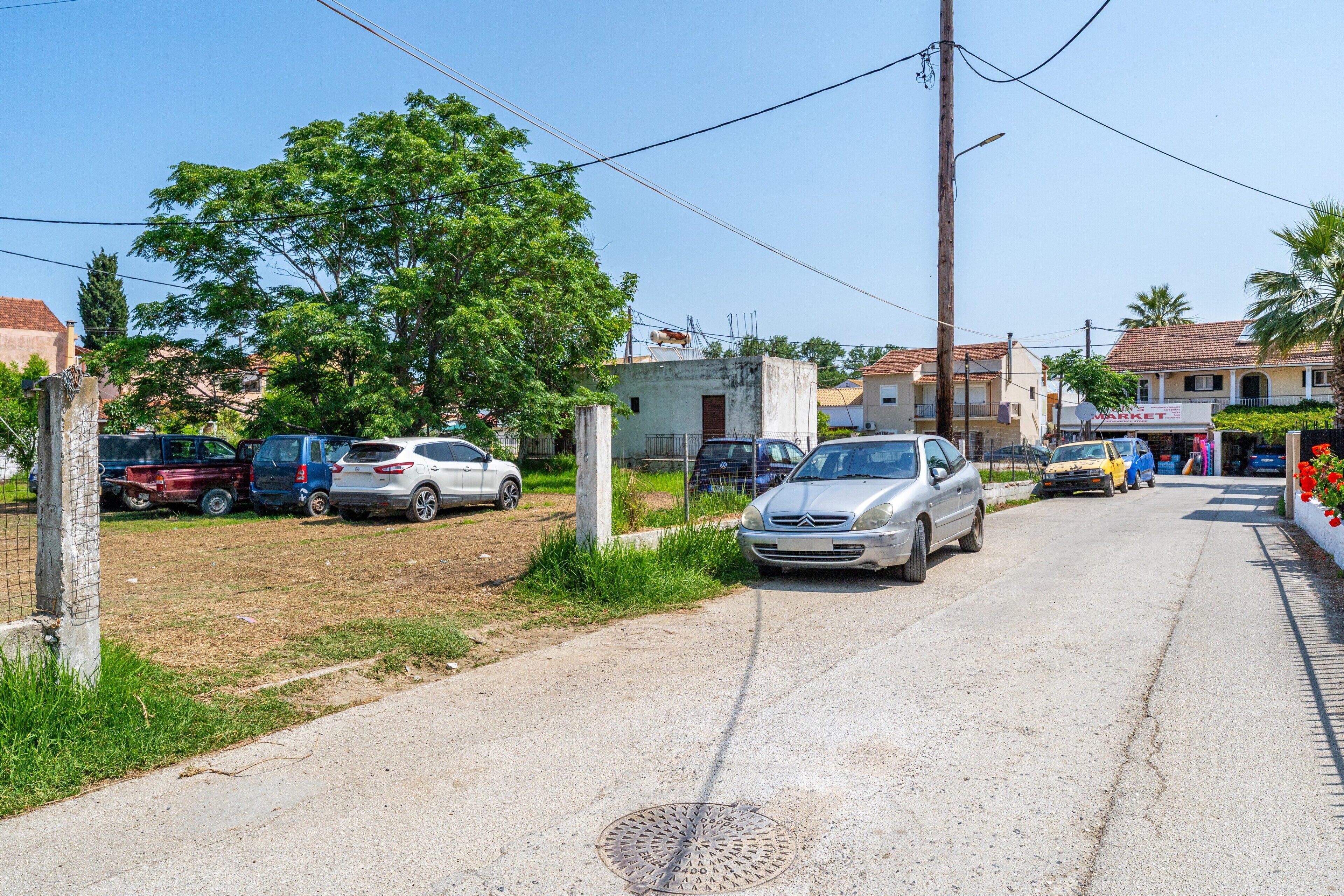 Una calle con coches estacionados, un edificio con un letrero y un cielo despejado.