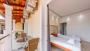 A hotel room with a balcony, a bed, a table with chairs, and a small kitchen area.