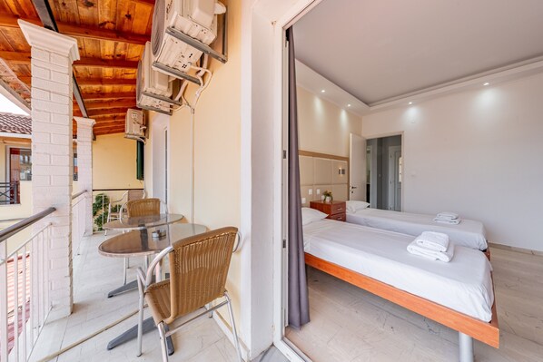 A hotel room with a balcony, a bed, a table with chairs, and a small kitchen area.