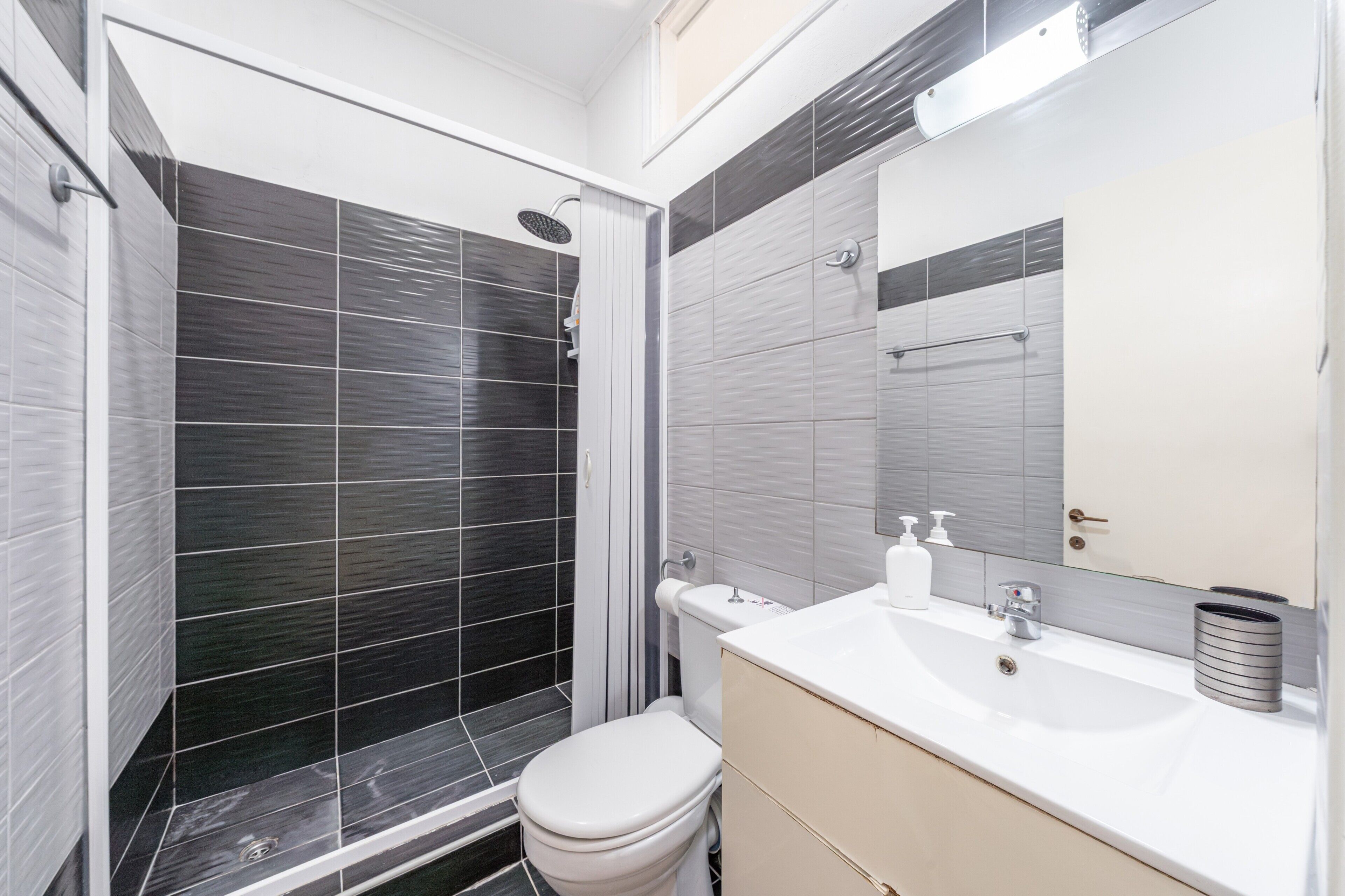 Une salle de bain moderne équipée d’une douche, de toilettes, d’un lavabo et d’un miroir.