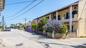 A street view with buildings, a parked car, and a flower box with purple flowers.