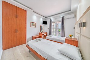 A hotel room with two beds, a desk, a wardrobe, and a TV. - Apartment 'Two Bedroom 3' with Wi-Fi and Air Conditioning (Kavos)