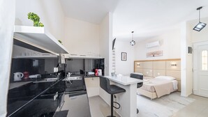 Una cucina moderna con piani di lavoro neri, un'isola bianca e un letto con testiera in legno.