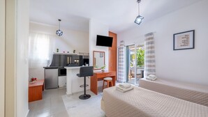 Una camera d'albergo moderna con angolo cottura, una scrivania, un letto e una televisione.