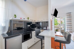 A modern kitchen with a black countertop, white cabinets, and a small island with bar stools.