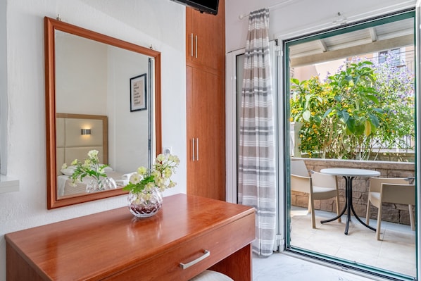 A bathroom with a wooden vanity, a mirror, and a vase with flowers.