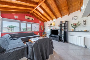 A living room with a wooden ceiling, a sofa, a TV, and a bookshelf.