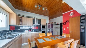 Una cocina moderna con armarios de madera, un lavamanos de acero inoxidable y un comedor con mesa y sillas de madera.