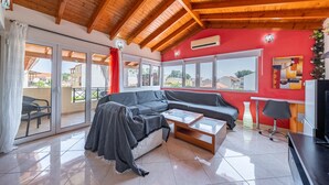 Una sala de estar moderna con techo de madera, una pared de acento roja, un sofá, una mesa de centro y un televisor.