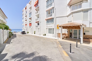 A multi-story residential building with balconies, a covered entrance, and a view of the sea. - Apartment 'Torresol 208' with Shared Pool, Wi-Fi and Air Conditioning (Nerja)