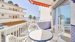 Een balkon met witte stoelen en een tafel, met uitzicht op zee.