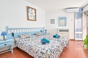 A bedroom with two beds, a desk, a chair, and an air conditioning unit. - Apartment 'Torresol 208' with Shared Pool, Wi-Fi and Air Conditioning (Nerja)