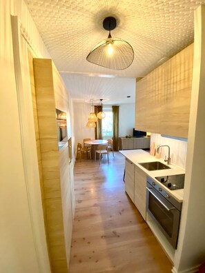Una cocina moderna con suelo de madera, una zona de comedor con mesa redonda e iluminación colgante.