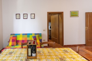 A room with a bed, a table with a bottle, and a door.