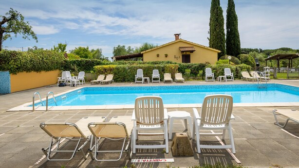 A swimming pool with lounge chairs, a pergola, and a building with a tiled roof. - Apartment 'Casa Milla - Bilocale Becaccia' with Shared Pool, Shared Terrace and Wi-Fi (Cecina)
