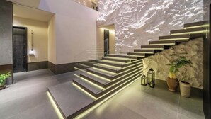 A modern interior with a staircase, a wall with a textured pattern, and a potted plant. - Songmo Hotel (Huzhou)