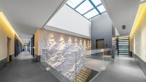 A modern hotel lobby with a glass staircase, a high ceiling, and a skylight. - Songmo Hotel (Huzhou)