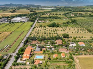 An aerial view of a residential area with houses, a swimming pool, and agricultural fields.