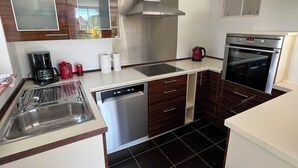 Una cocina compacta con lavavajillas, estufa y una ventana sobre el fregadero.