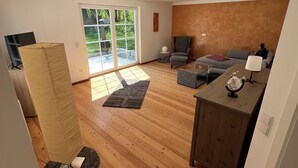 Una sala de estar moderna con suelo de madera, un sofá, una mesa de centro y un televisor.