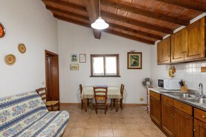 Una cocina con armarios de madera, una mesa de comedor con sillas, un microondas y un lavabo.