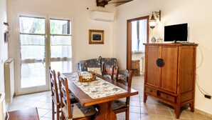 A dining area with a table set for four, a wooden cabinet, and a television on a stand.