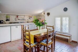 Une cuisine avec une table à manger, des chaises, une horloge et une fenêtre donnant sur un beau paysage.