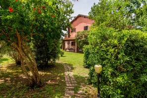Un sentier de jardin menant à une maison, avec un banc en pierre et un lampadaire.