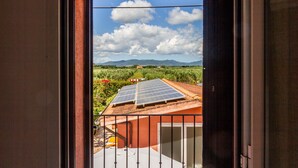 Un balcon doté de panneaux solaires, une vue sur des champs verdoyants et des montagnes lointaines.
