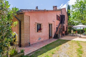 Ein Gebäude mit Ziegelaußenwand, einer Treppe und einer kleinen Terrasse mit Außenbestuhlung.