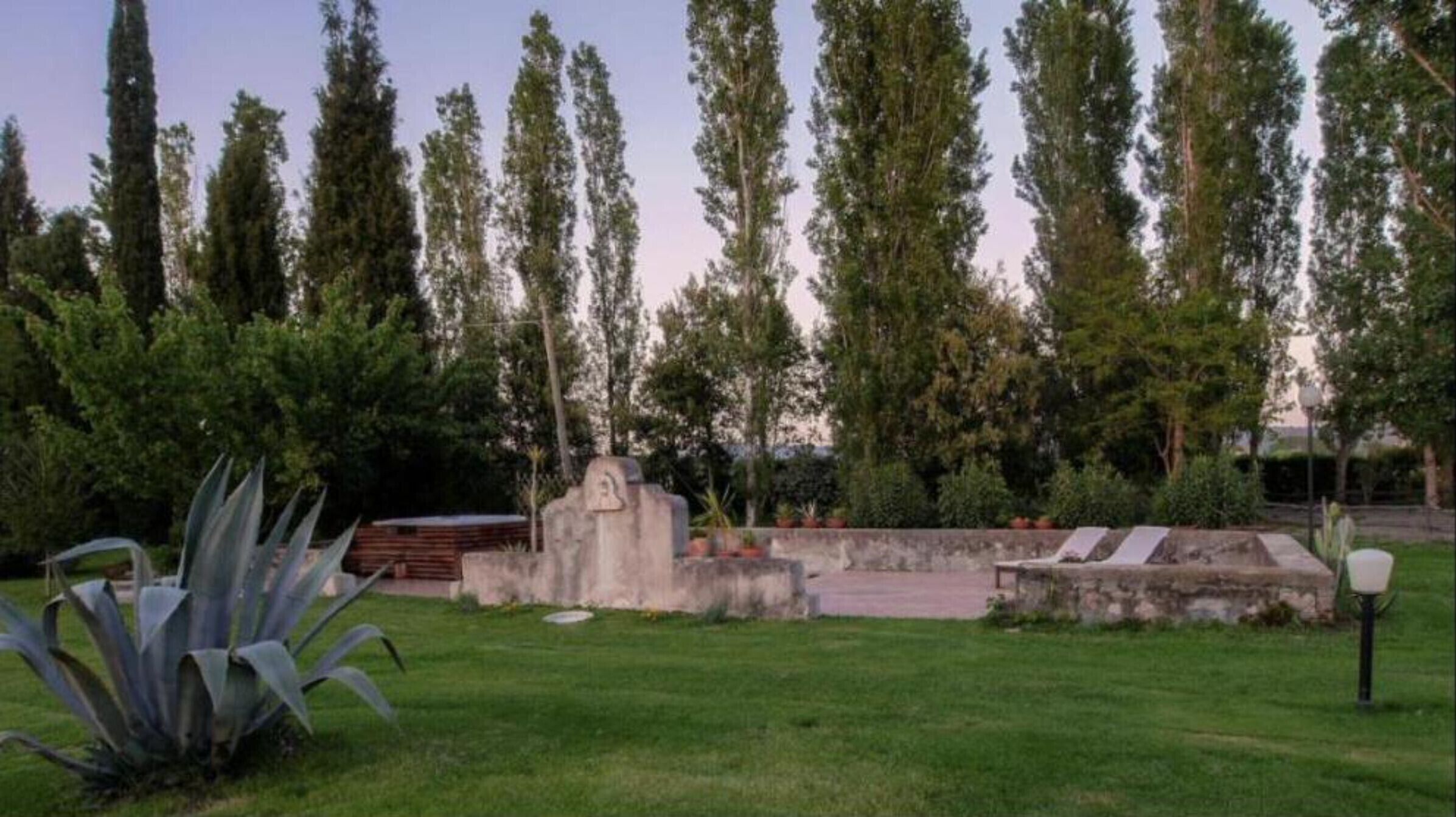A cemetery with a stone monument, a bench, and a lamppost.