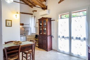 A dining area with a wooden table, chairs, a cabinet, and a window with a view. - Apartment 'Aia' with Private Garden, Wi-Fi and Air Conditioning (Bagno Roselle)