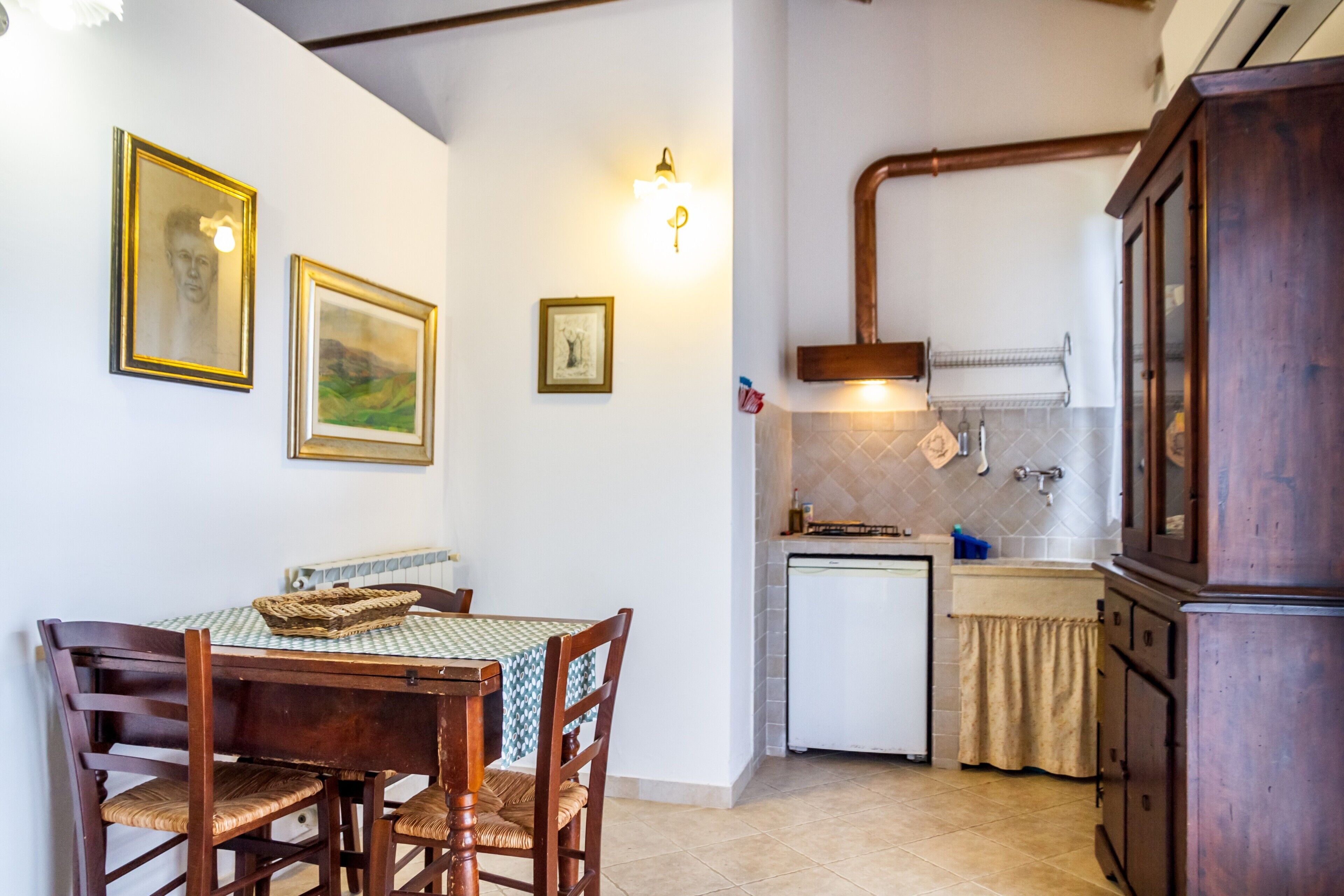 Une cuisine compacte comprenant une table à manger, des chaises et un petit réfrigérateur.