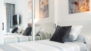 Una habitación de hotel con una cama, un televisor y obras de arte en la pared.