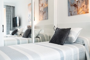 A hotel room with a bed, a television, and artwork on the wall.