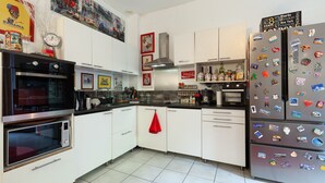 Een keuken met witte kastjes, een roestvrijstalen koelkast en een magnetron.