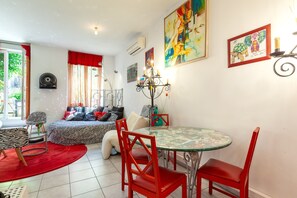 Ein modernes Wohnzimmer mit Glastisch, roten Stühlen, einem Sofa mit Zeprazebra-Muster und einem roten Vorhang.