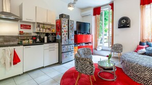 Een moderne keuken met witte kastjes, een rode koelkast en een flatscreen televisie.