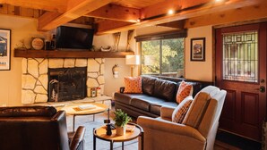 A cozy living room with a stone fireplace, leather furniture, and a wooden ceiling.