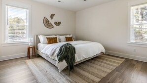 Ein Schlafzimmer mit Bett, Deckenventilator, Nachttisch und großem Fenster.