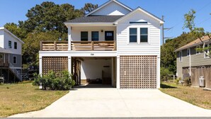 Ein zweistöckiges Haus mit Veranda, Garage und einer kleinen Terrasse.