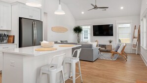 Une cuisine moderne avec des meubles blancs, un réfrigérateur en acier inoxydable et un îlot central doté de tabourets.