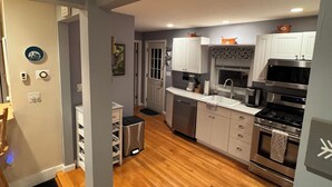 Una cocina moderna con suelo de madera, armarios blancos y electrodomésticos de acero inoxidable.