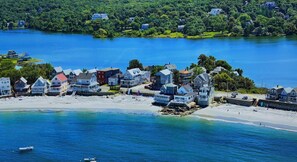 A coastal town with houses by the water, a sandy beach, and boats.