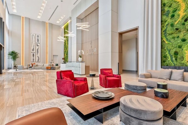 Um lobby espaçoso com design moderno, com balcão de recepção, áreas de estar e uma grande parede verde.