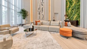 A modern living room with a large sectional sofa, a coffee table, and a potted plant. - Stylish Studio | Pool View | Downtown Doral' Heart (Doral)