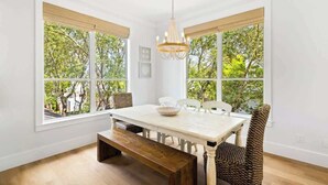 A dining area with a table, chairs, a bench, and a chandelier.