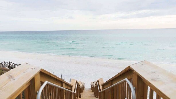 A wooden staircase leading to a beach with a view of the ocean.