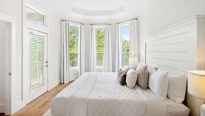 A bedroom with a large bed, a ceiling fan, and multiple windows.